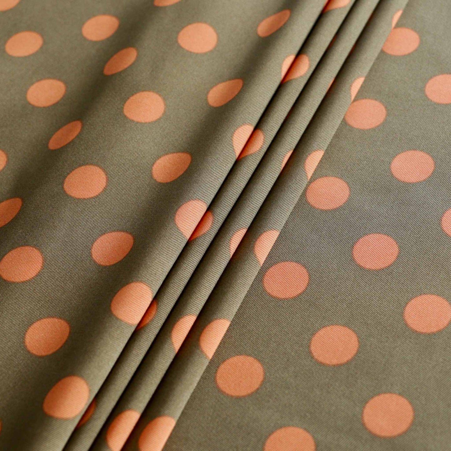 large polka dot design in peach on beige sating dressmaking fabric