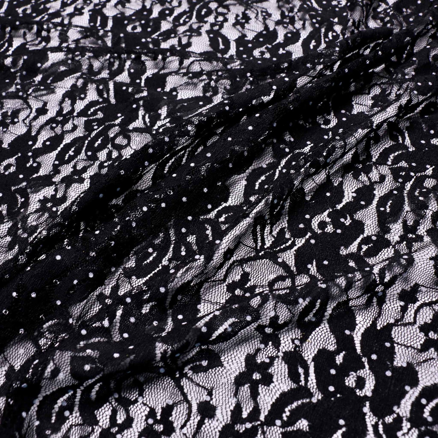 white polka design on floral black stretchy lace dressmaking fabric