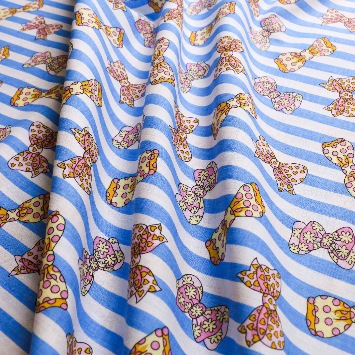 blue pink sustainable retro cotton dressmaking fabric with bow and stripe design