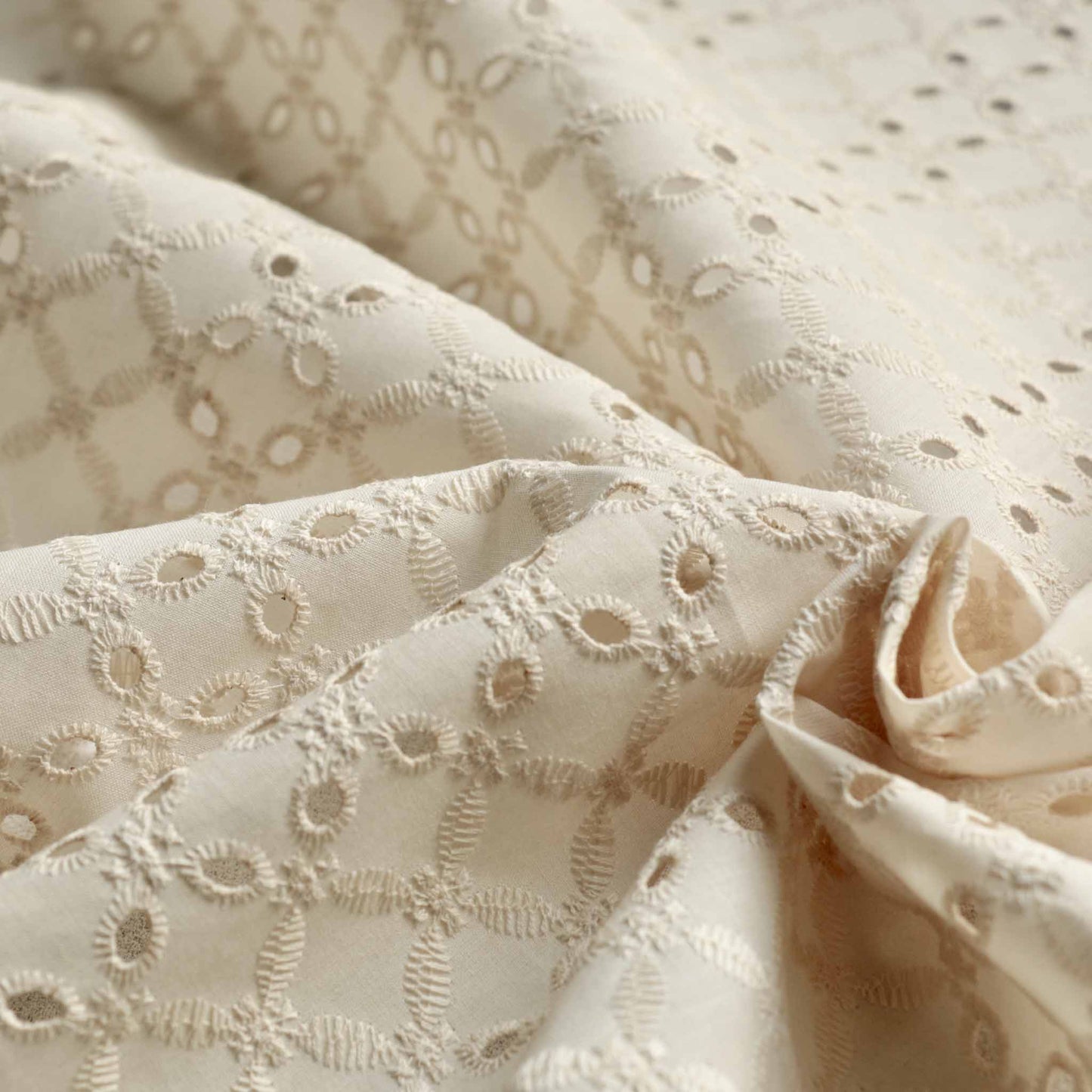 cream broad anglaise dressmaking fabric with 4 hole embroidery design