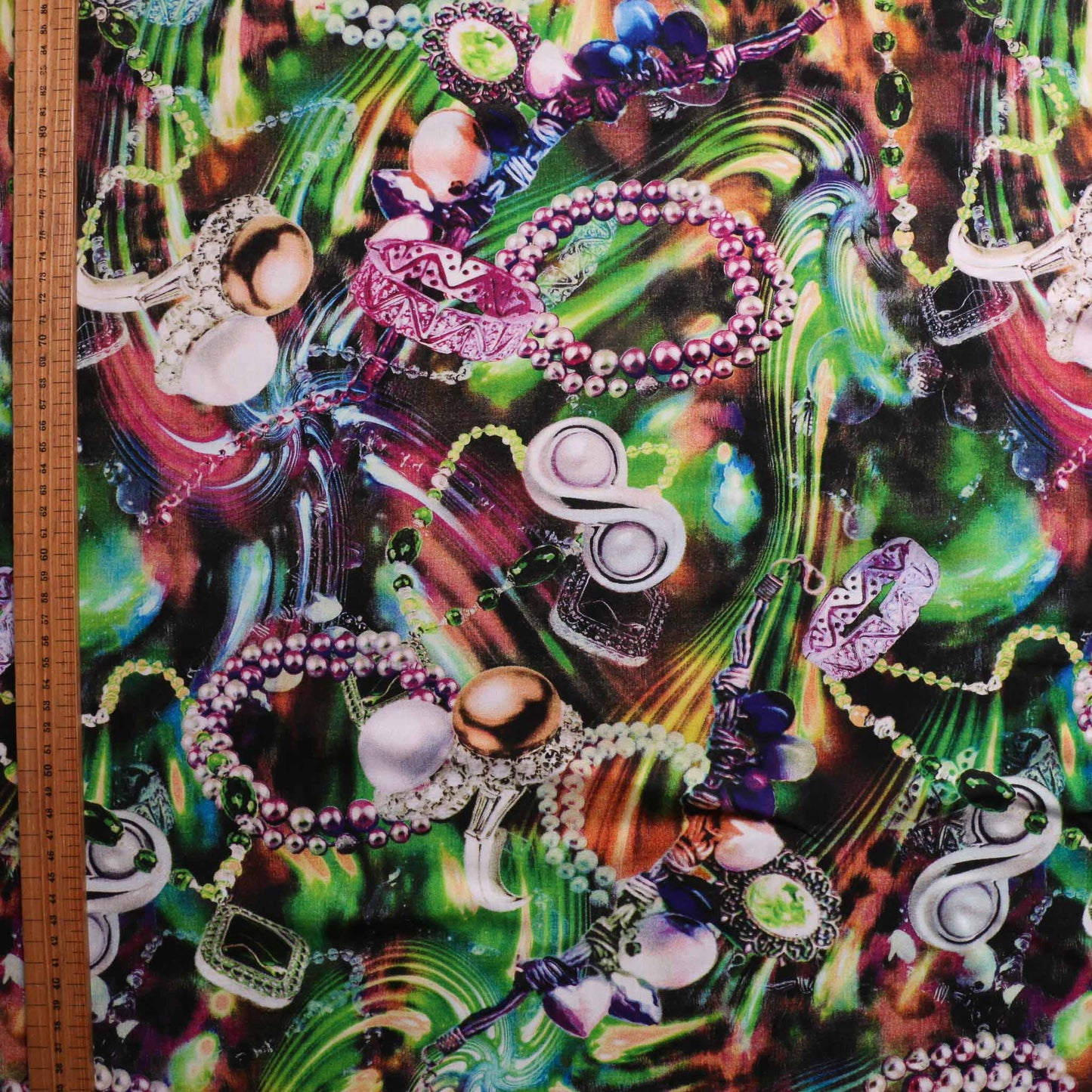 metre green viscose challis dressmaking fabric with striking jewellery print in orange purple and blue