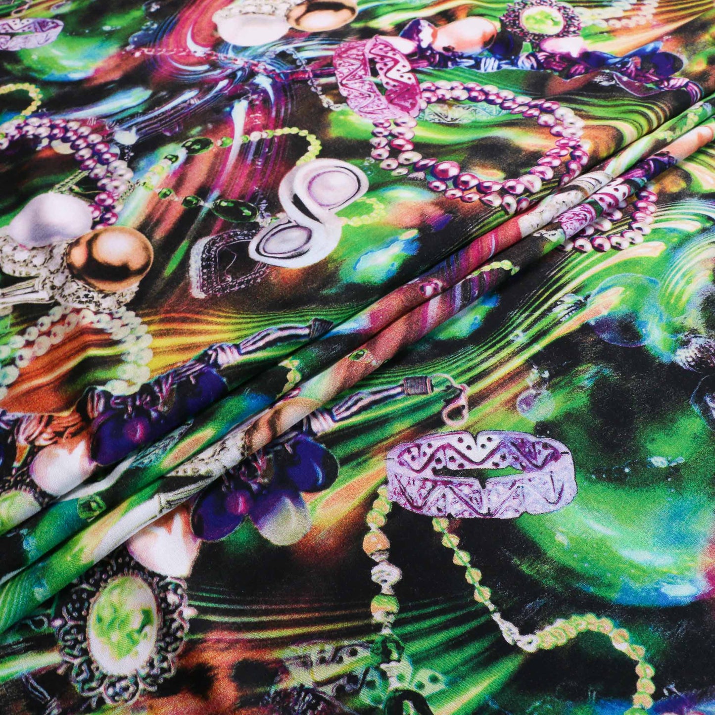 folded viscose challis dressmaking fabric in green purple and blue with printed jewellery pattern