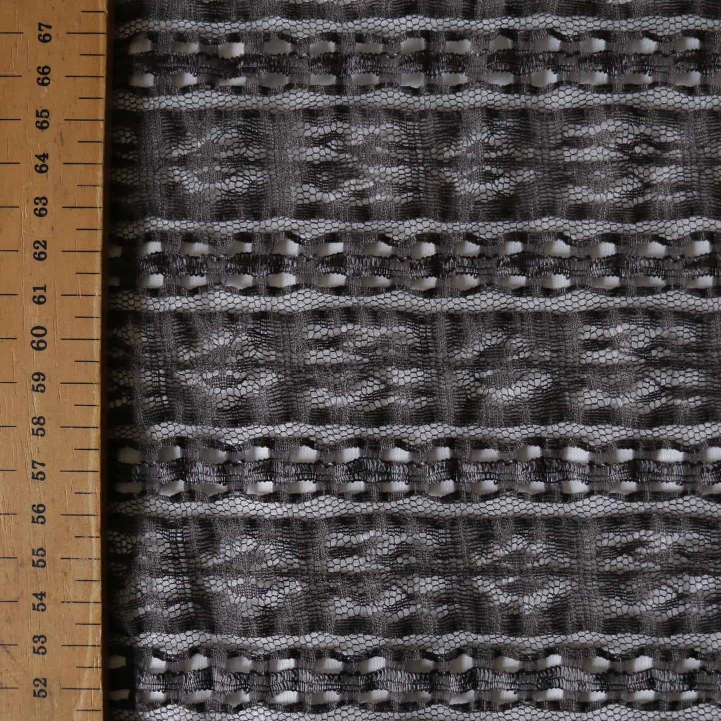 satin ribbon running through delicate lace dressmaking fabric in grey