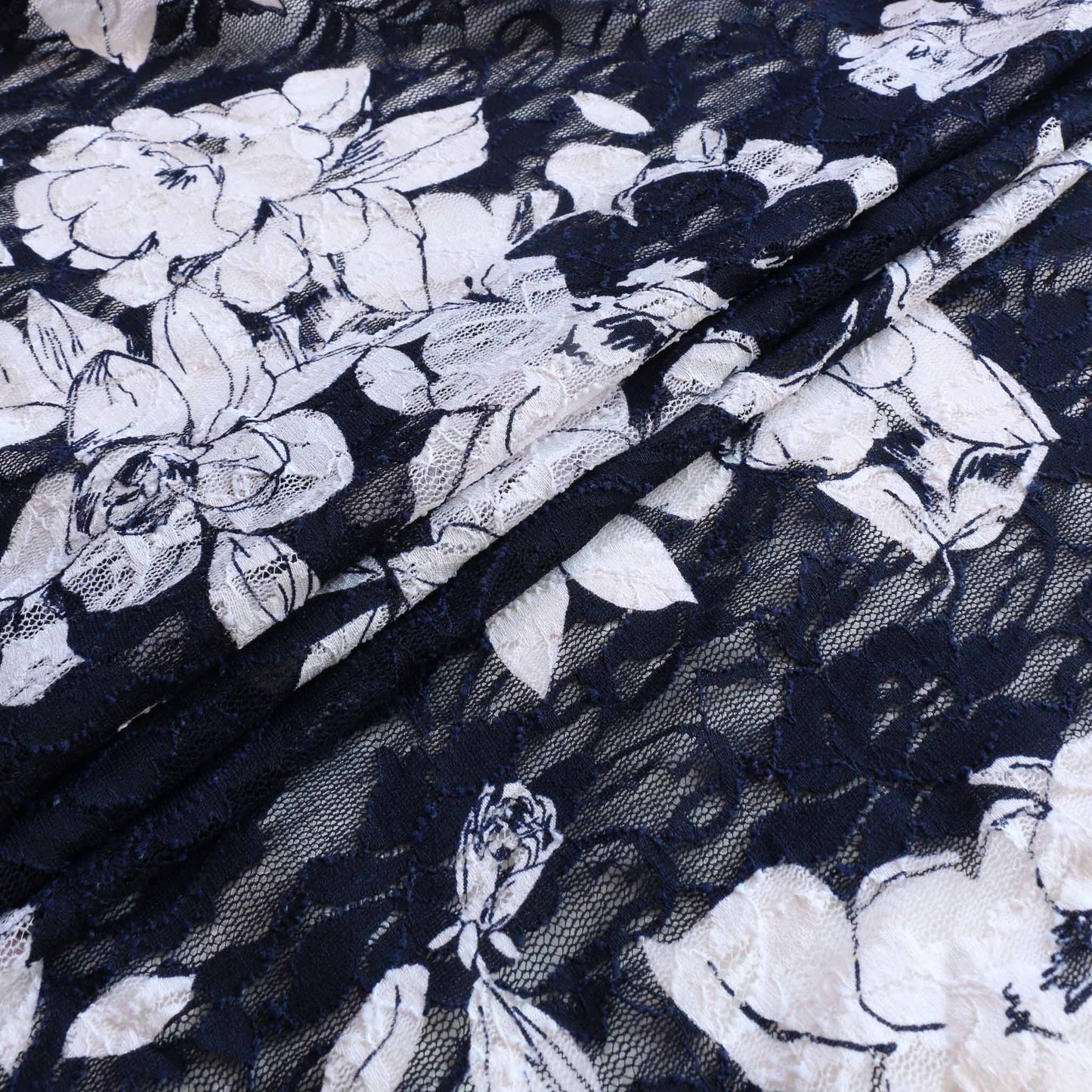 stretchy lace dressmaking fabric in navy blue with large white floral pattern