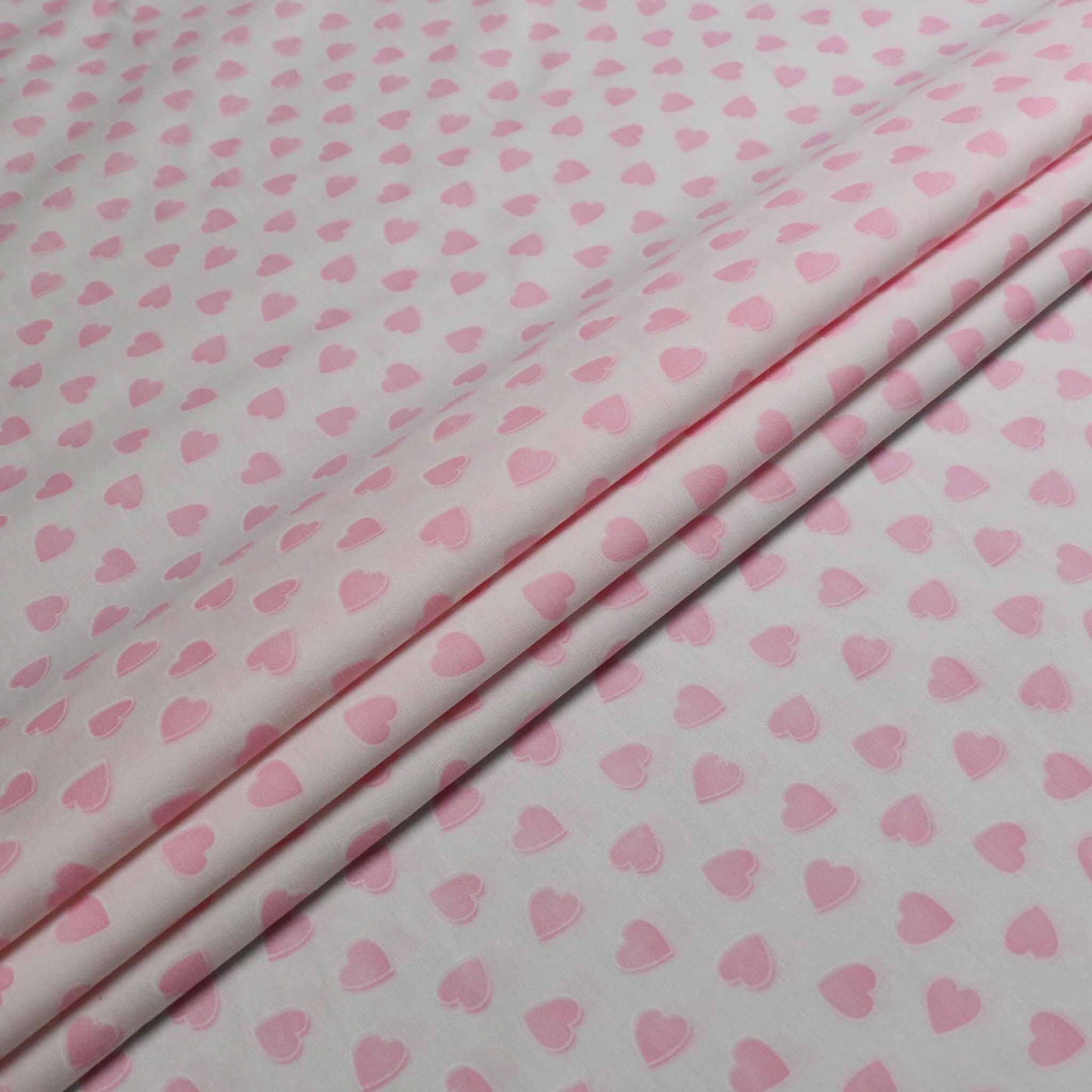 pink love hearts printed on white cotton poplin dressmaking fabric