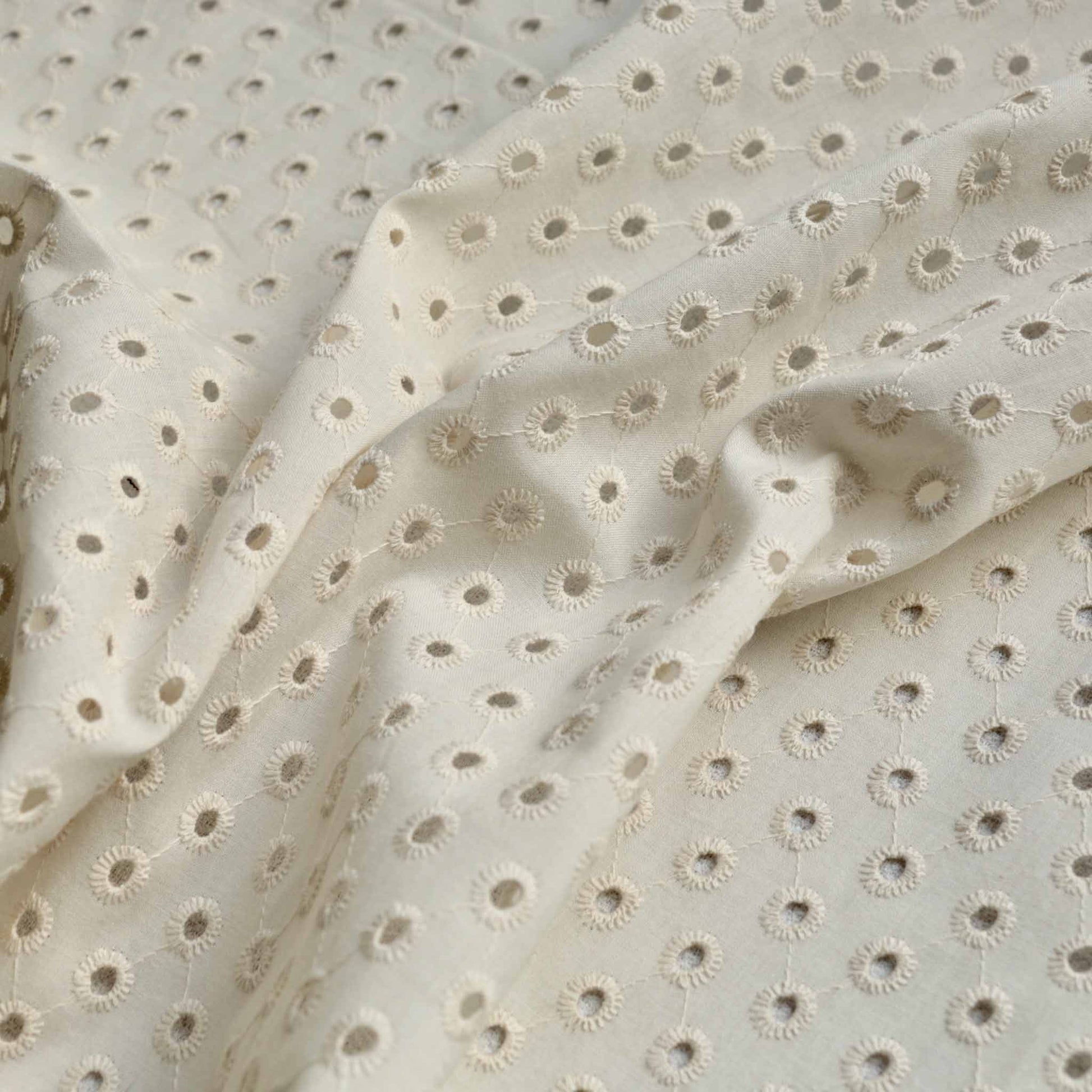 cream coloured one hole broad anglaise dressmaking fabric with delicate design