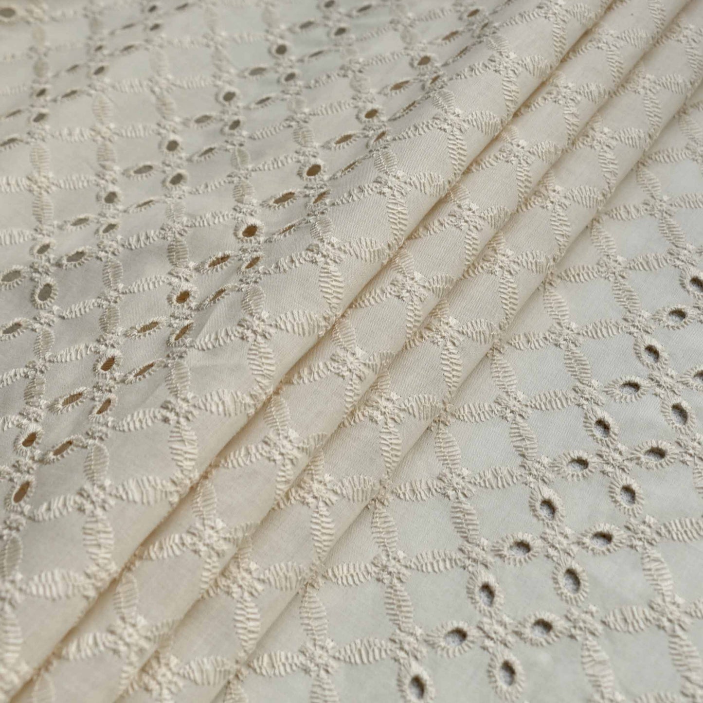 folded cream broad anglaise dressmaking fabric with 4 hole pattern