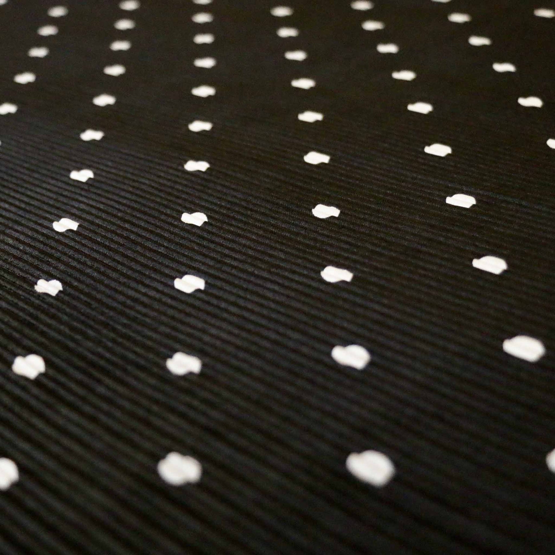black stretchy plisse dressmaking fabric with white polka dot pattern