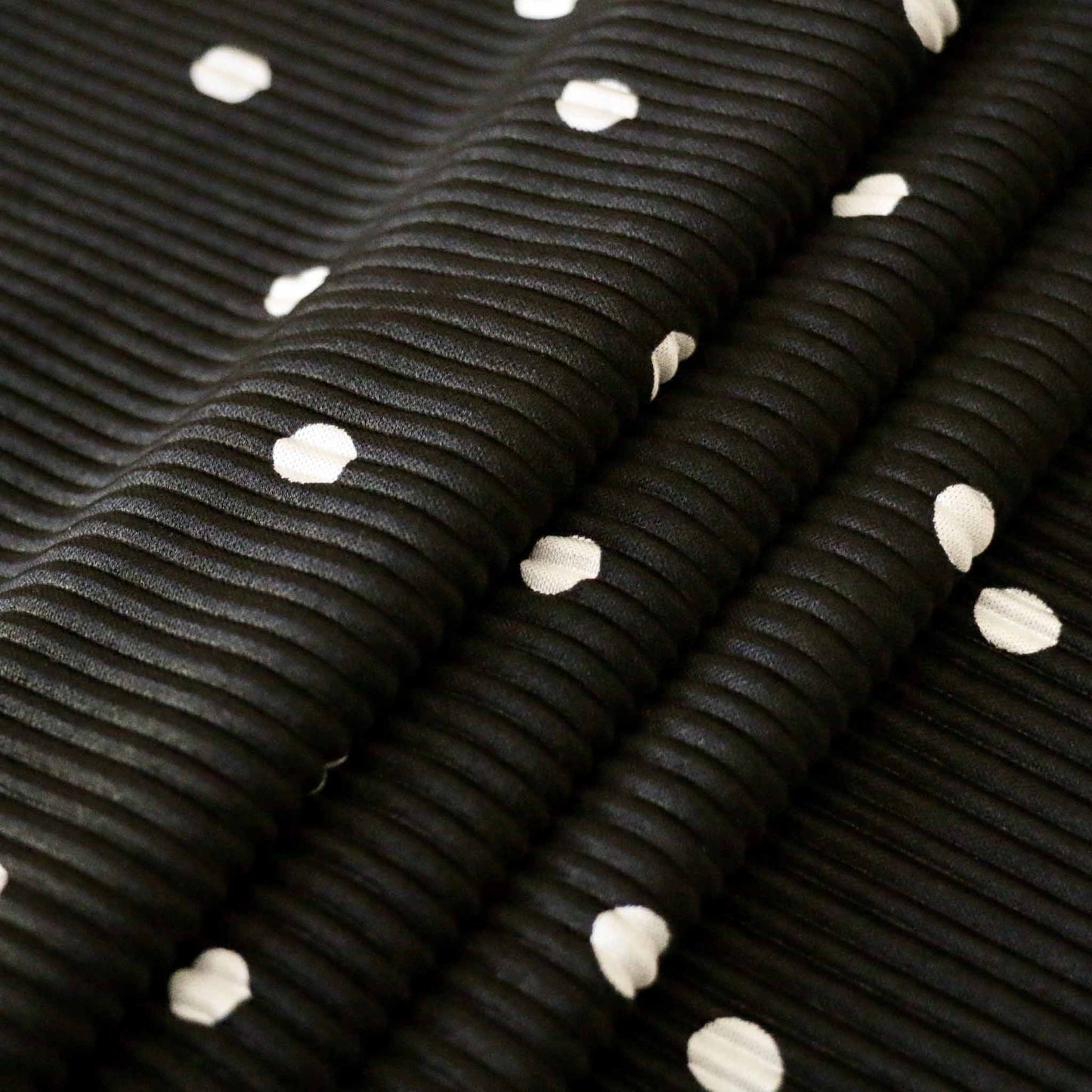 black plisse dressmaking fabric with white polka dot design