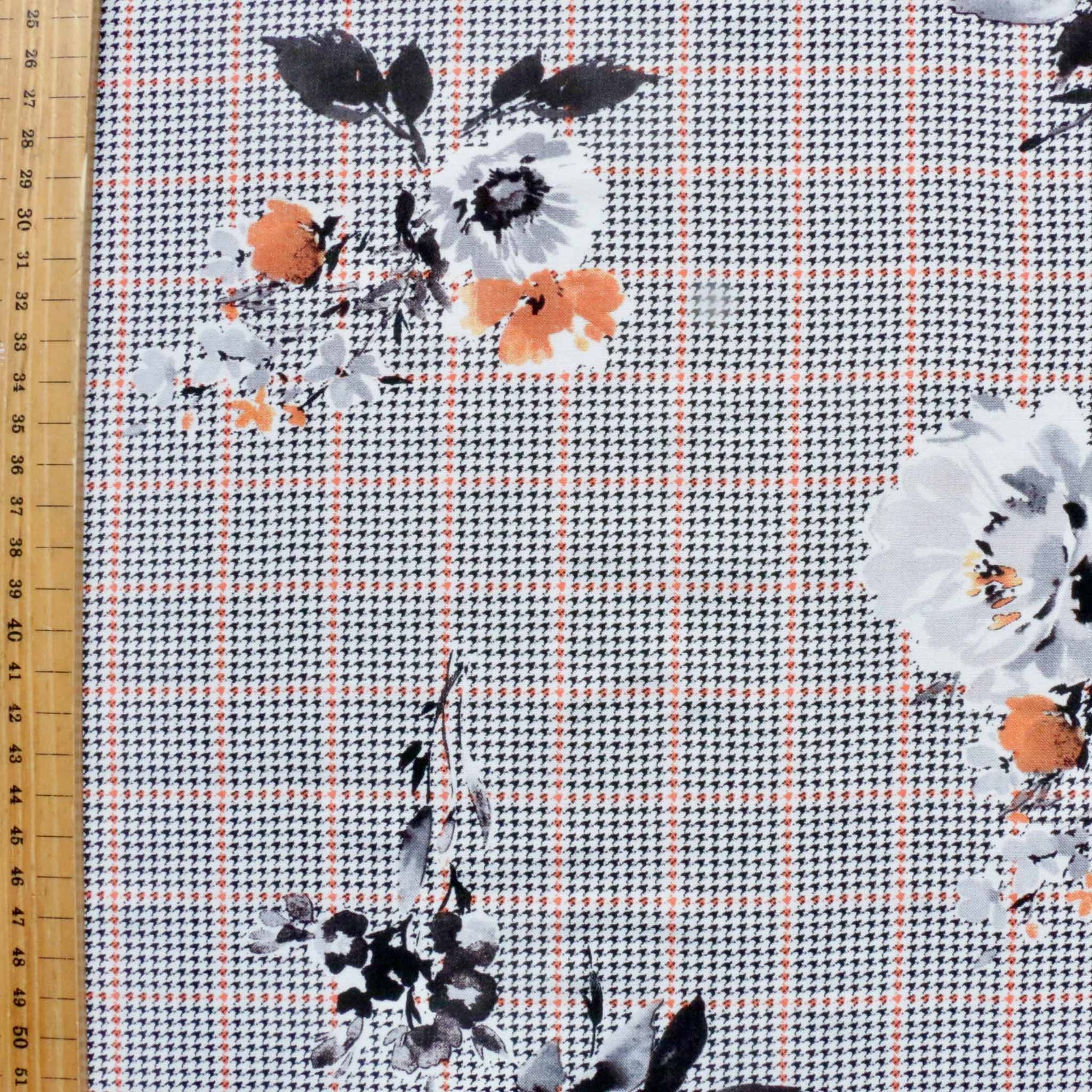metre viscose challis dressmaking fabric with black houndstooth check pattern and white and orange floral print