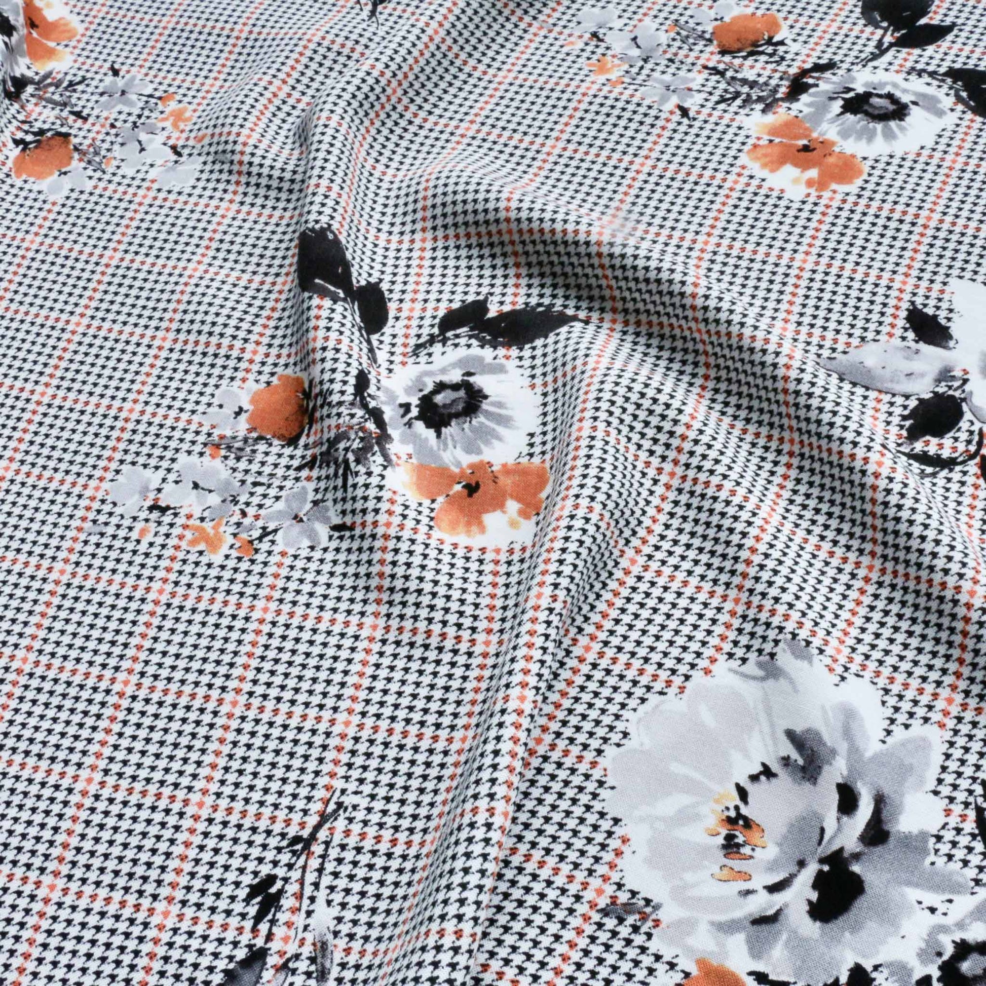 black houndstooth patterned viscose challis dressmaking fabric with flowers printed in white and orange