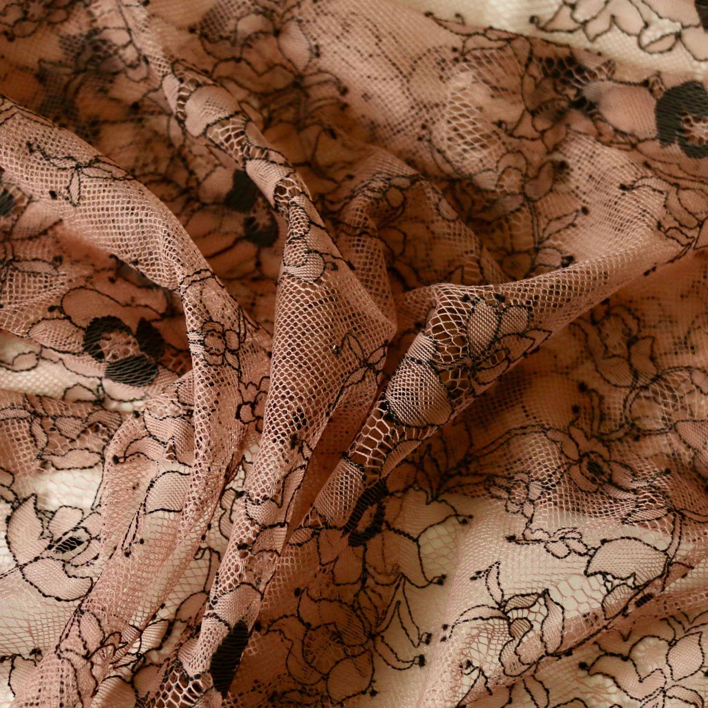 black floral design on pink delicate nylon dressmaking lace fabric