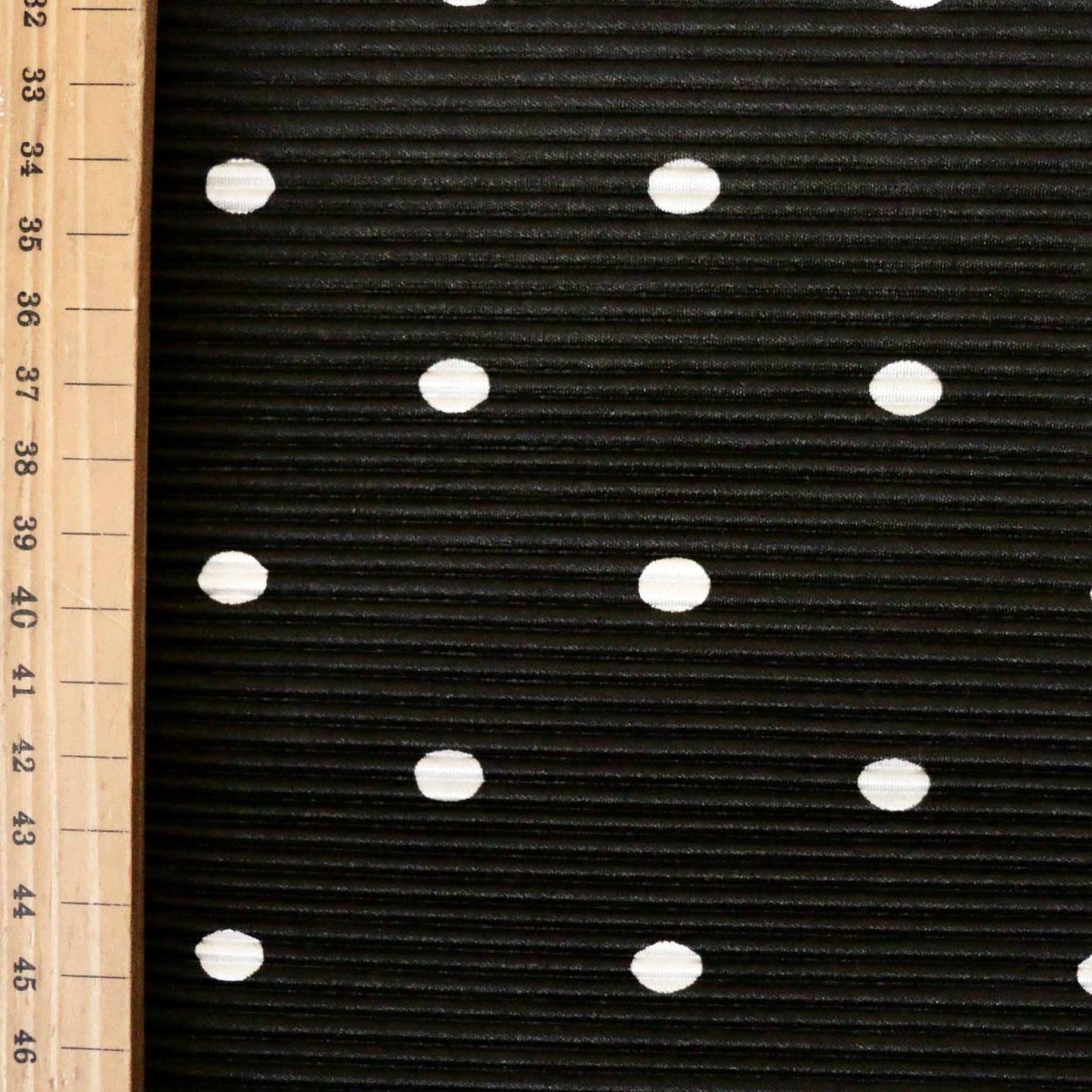 metre black plisse dressmaking fabric with white polka dots printed