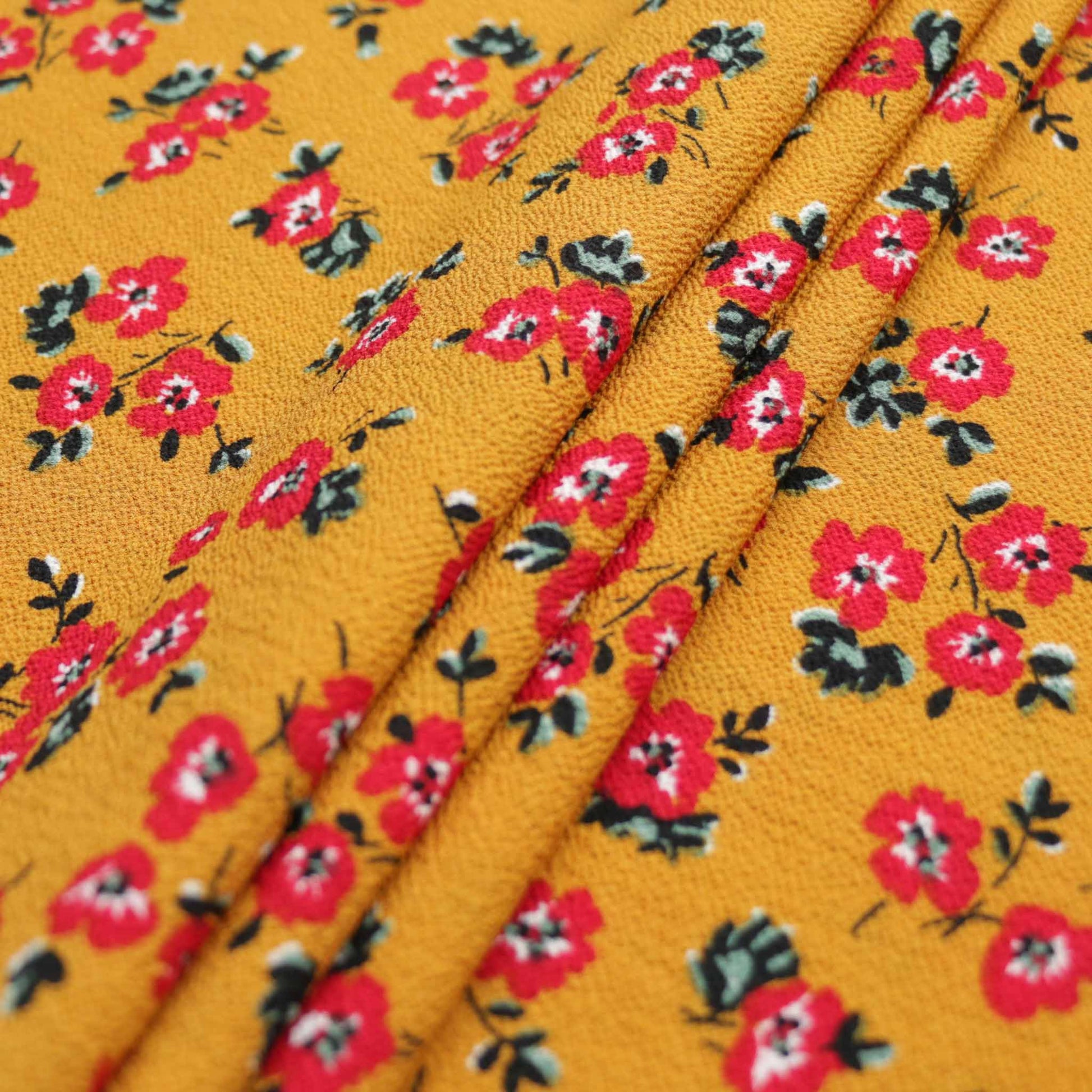 folded bubble crepe dressmaking fabric with red flowers printed on mustard base