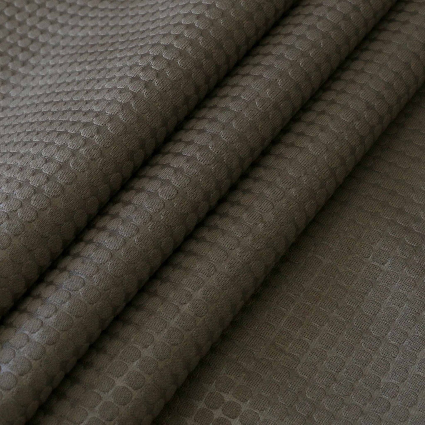 folded grey jersey scuba fabric in grey with oval jacquard polka dot pattern