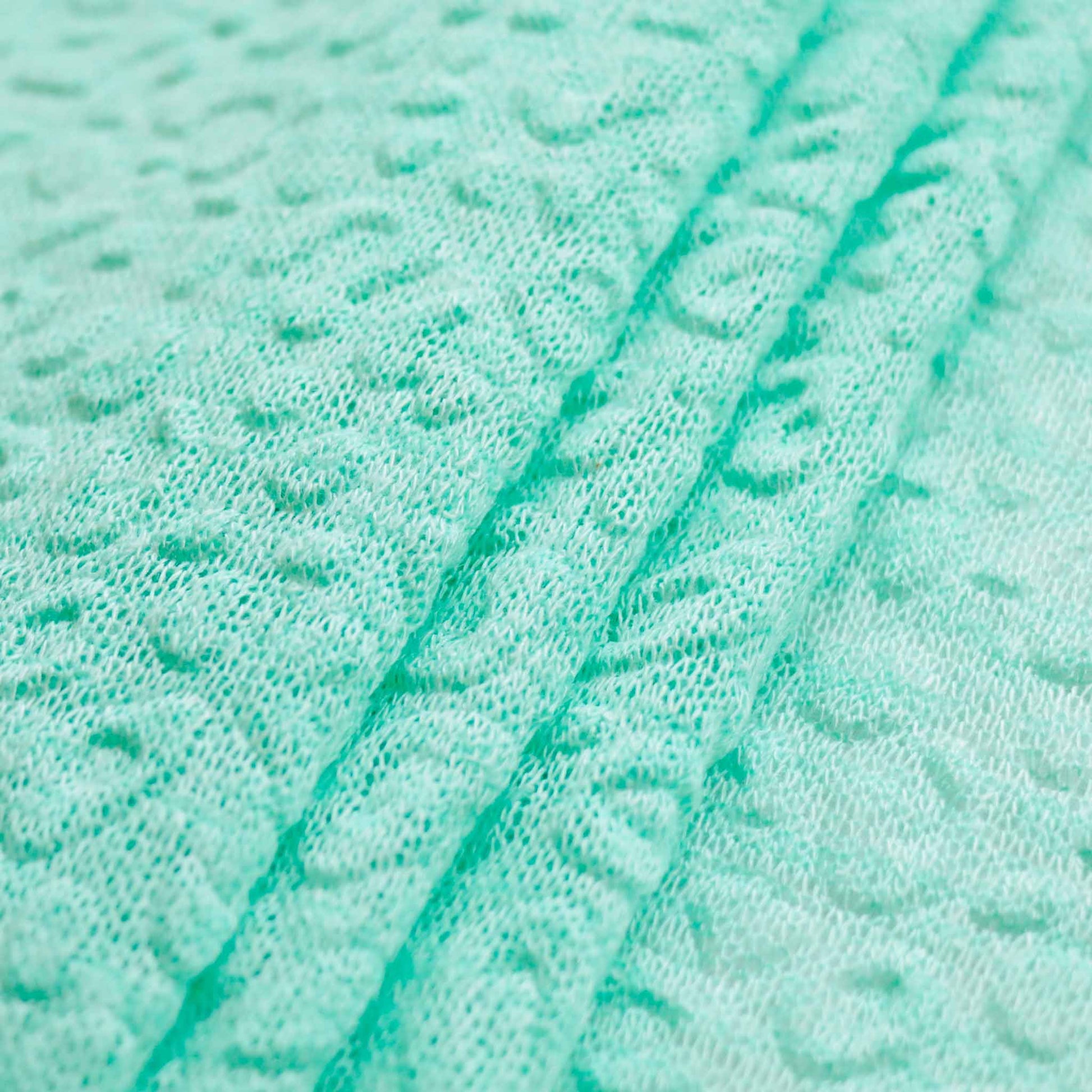 folded mint green jersey knit dressmaking fabric with decorative embossed texture