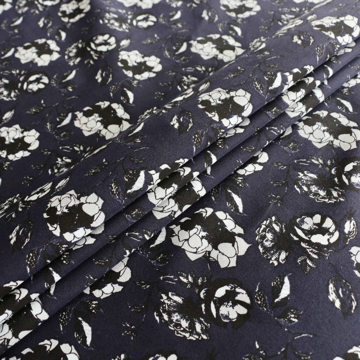 folded navy cotton sateen dressmaking fabric with white and black floral print