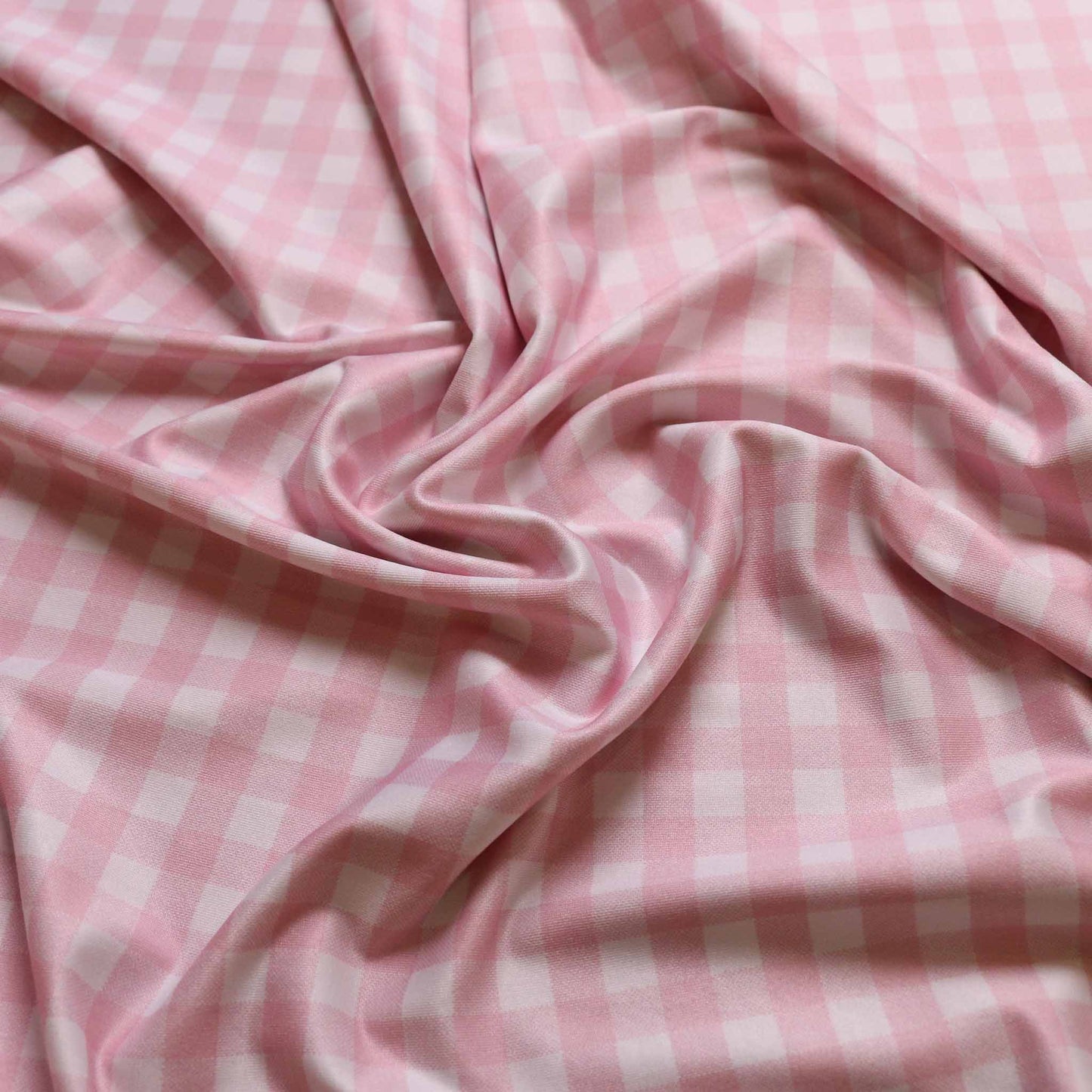 folded dressmaking lycra jersey fabric with white and pink gingham print design