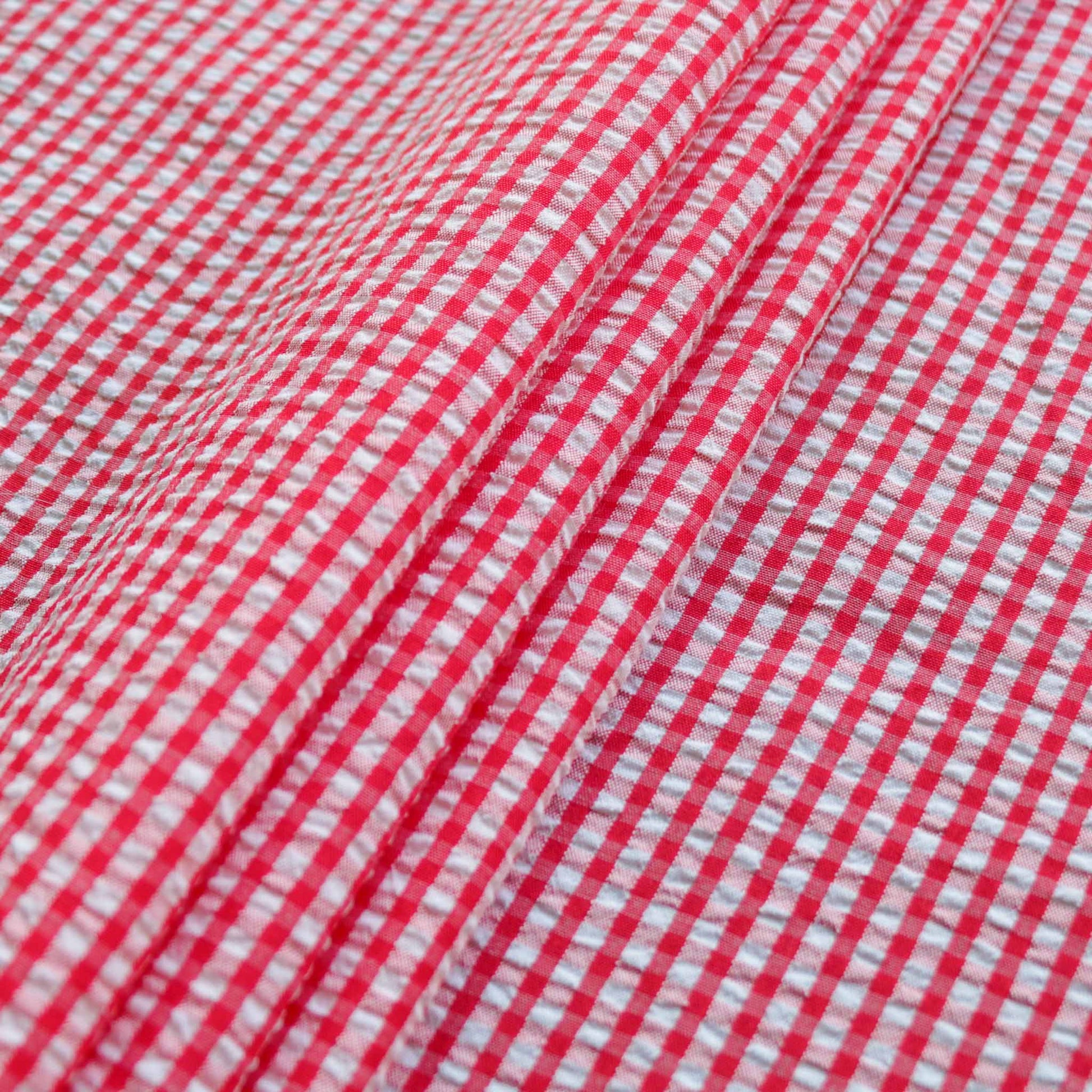 folded red and white seersucker dressmaking fabric with gingham style design