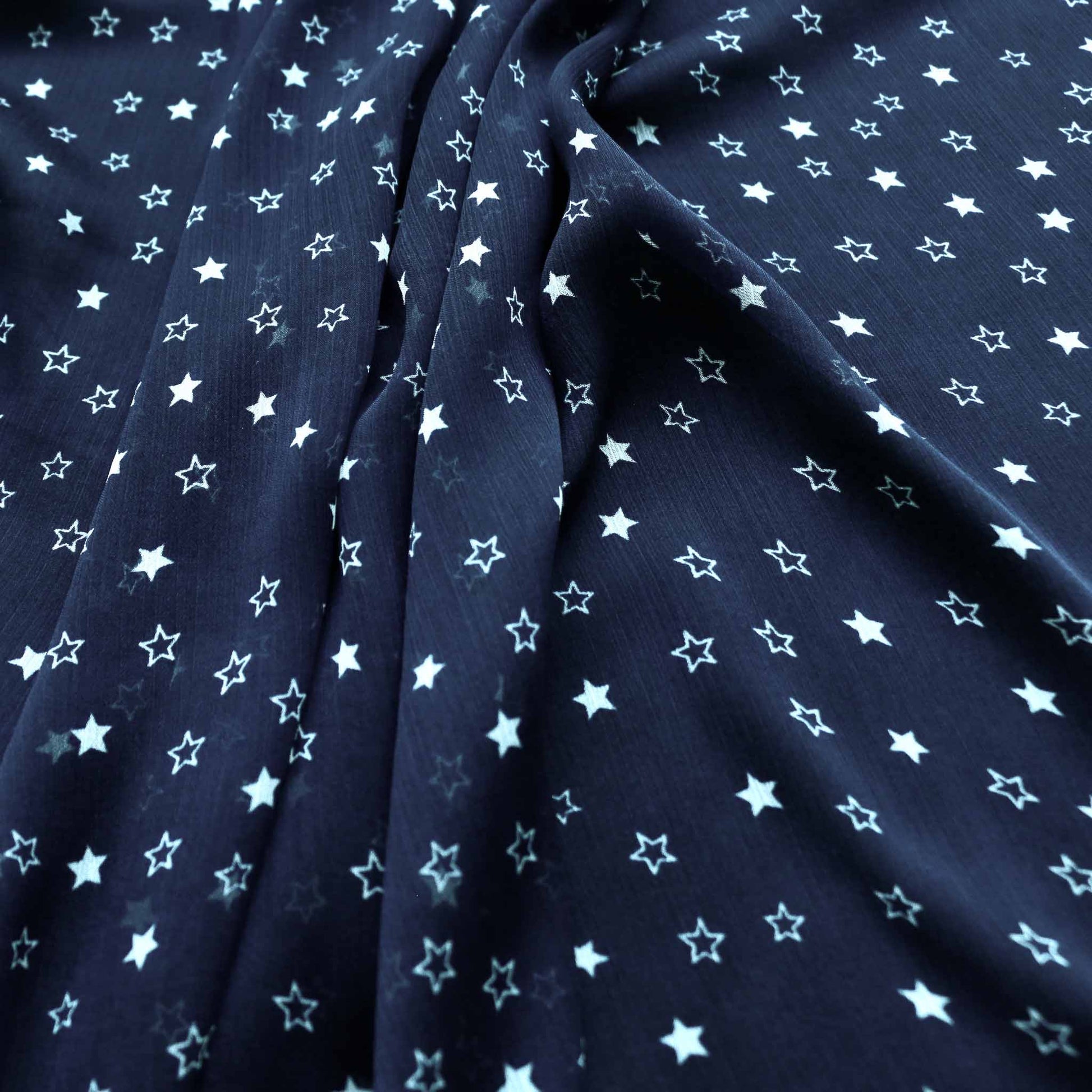 white star design printed on blue crinkle polyester chiffon dressmaking fabric