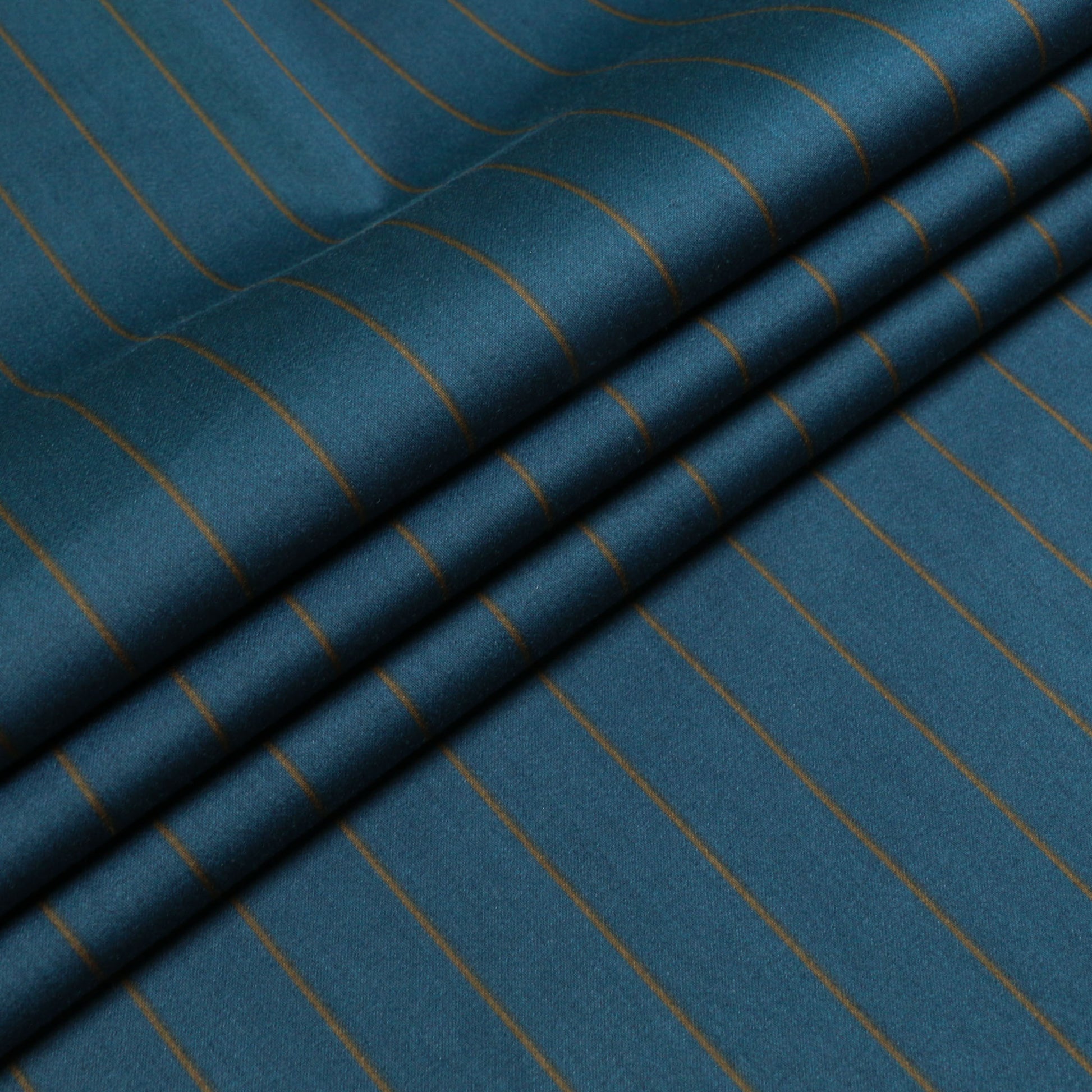 folded beige and teal cotton pinstripe dressmaking fabric