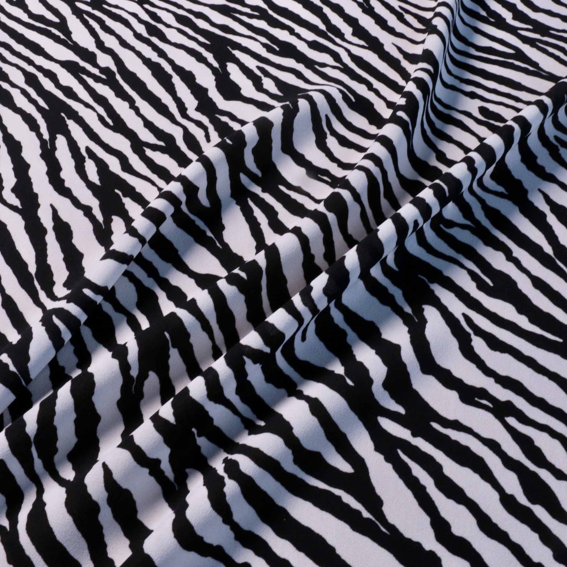 white georgette dressmaking fabric with black animal print zebra skin pattern