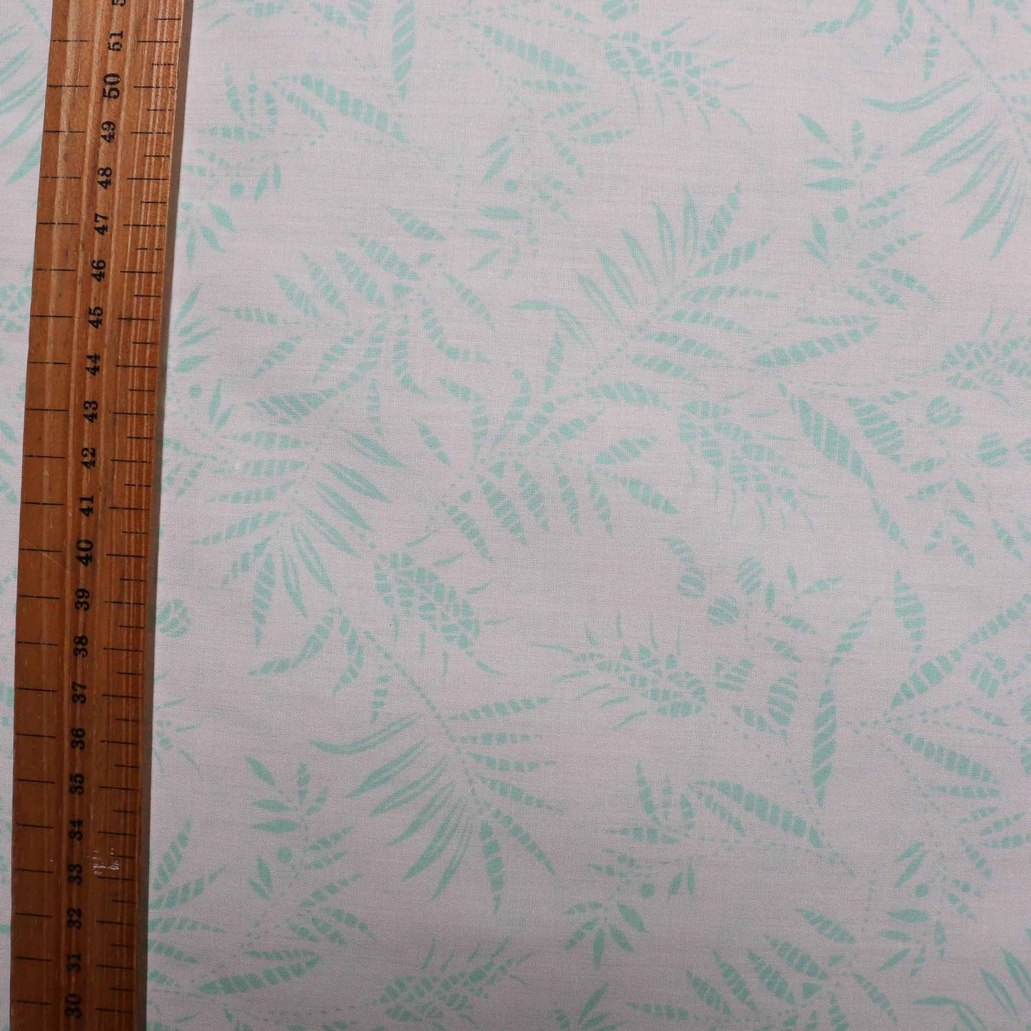 polyccotton dressmaking fabric in white with mint colour leaves printed