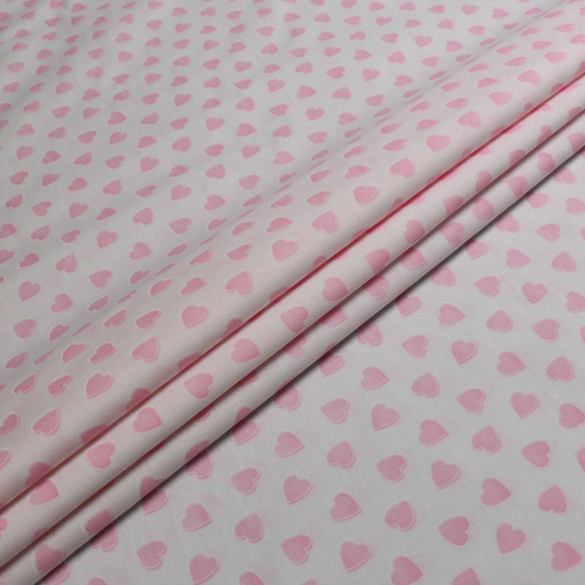 pink love hearts printed on white cotton poplin dressmaking fabric