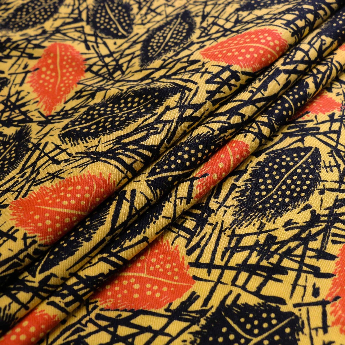 folded yellow sustainable vintage cotton twill dressmaking fabric with orange and black printed leaves